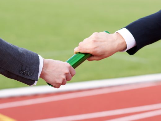 Businessman passing green baton in relay race