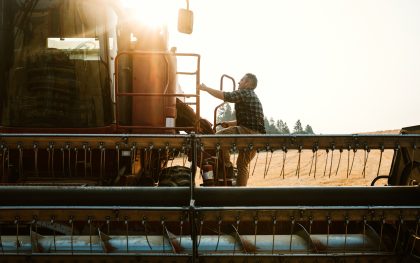 Farmer Climbing In To Combine Harvester In Idaho Wheat Field