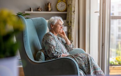 Elderly woman sitting in an armchair in her home