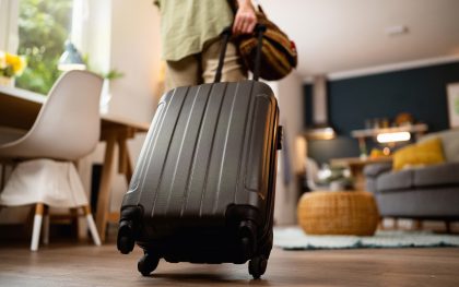 Unrecognizable woman pulling suitcase into apartment