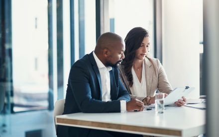 Office, woman and man with contract, consulting and financial advice for business plan or audit report. Accounting, finance and businessman with tax advisor checking paperwork for review or feedback.